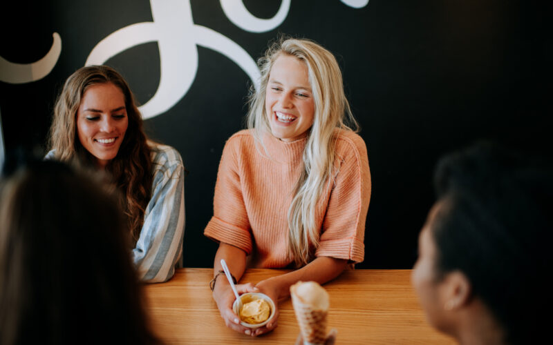 Friends sharing ice cream scoop, cone, and pint.